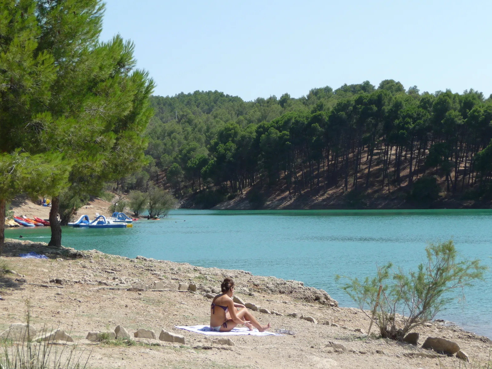 A quiet shore with kayaks and pedalos across the water