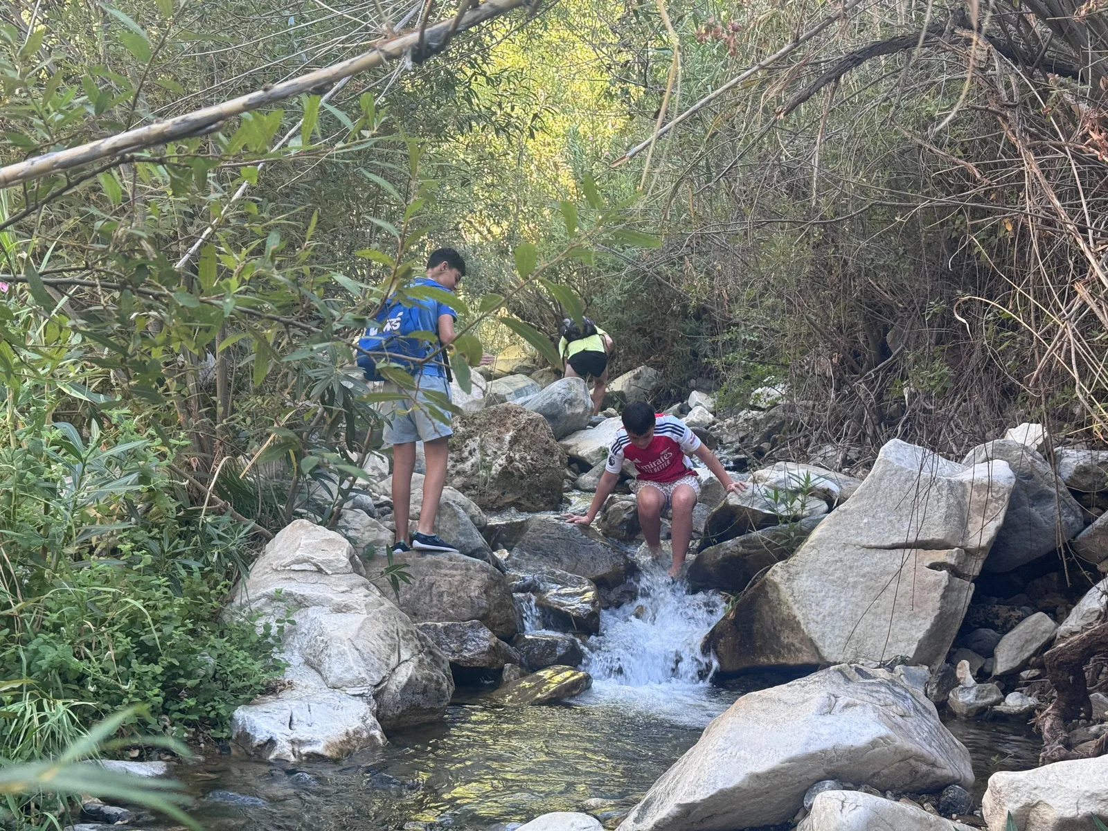 Kids scrambling up the stream between the boulders